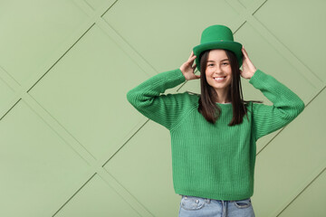 Beautiful young woman in leprechaun hat on green background. St. Patrick's Day celebration