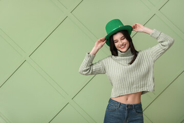 Beautiful young woman in leprechaun hat on green background. St. Patrick's Day celebration