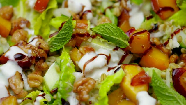 Close up of healthy salad, nectarine and walnut lunch plate spinning in close up. Wholefoods and vegetarian dishes. Plant based vegan food. High resolution 4k cooking shallow depth of field footage.