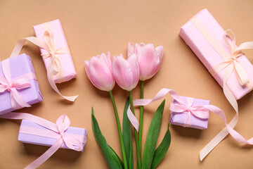 Gift boxes and pink tulips on beige background. Top view