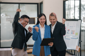 Joyful asian business team celebrating success with raised hands in office. Corporate victory and team achievement concept.