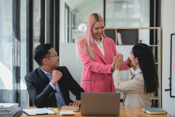 Happy asian business colleagues giving high-five in office setting. Team success and partnership concept.