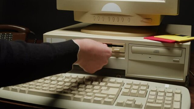 Using diskette FDD for old computer close-up. Hand inserting and ejecting Floppy Disk into vintage PC. Music recorder, playing retro computer games. 
