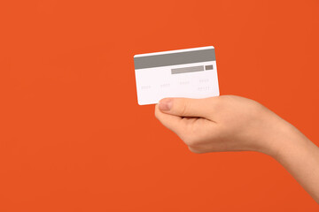 Female hand with credit card on orange background
