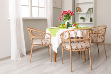 Interior of dining room with wicker chairs and table setting for Easter celebration