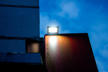Spotlight, LED lamp, industrial glowing lantern on the wall of a building at night.