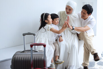 Excited Asian muslim family making high five together before going back home or mudik on Eid Mubarak moment.