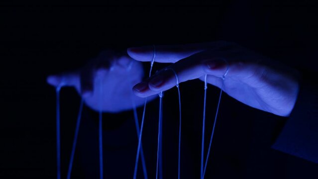 The puppeteer controls the puppets in the theater in blue neon light close-up. Managing people at work, in politics and government. Action control
