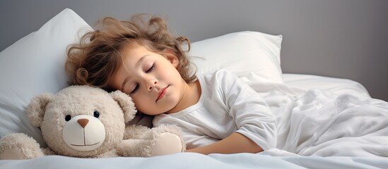 A little girl is lying in a white bed with a teddy bear, showcasing a peaceful and restful moment of well-being and comfort.
