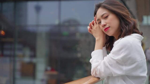 happy young asian woman relax daydreaming in the urban city street