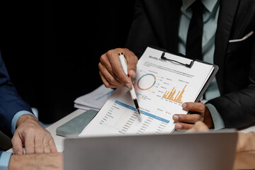 Three businesspeople are brainstorming together in a conference room about documents that need to be edited on the table, Colleagues are exchanging ideas about business strategies.