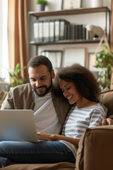 Multiracial couple enjoying quality time together using laptop on home sofa