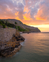 Vibrant colorful sunset over a dramatic rugged coastline surrounded by cliffs. Llandudno North Wales