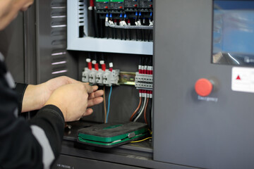 electrician connecting wires in control cabinet