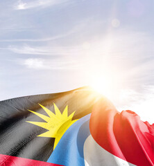 Antigua and Barbuda flag in waving in beautiful sky with sunlight.
