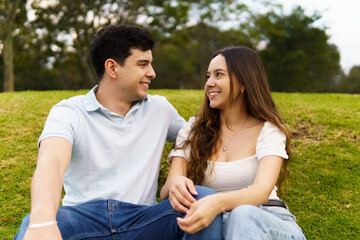 Obraz premium A young couple in love looking at each other sitting in a park