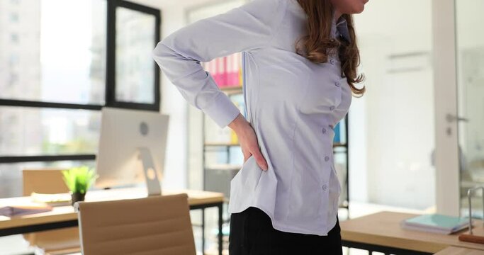 Businesswoman experiences back pain while standing in office