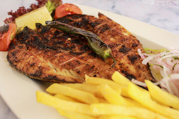 Grill Supreme Fish with french fries served in dish isolated on table closeup top view of grilled seafood