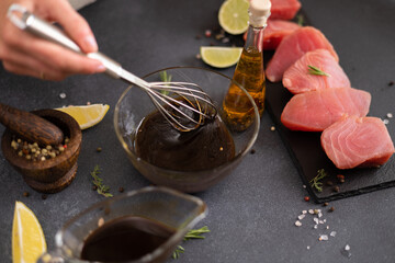 Woman mixing with whisk soy sauce and olive oil in a glass bowl making marinade to marinate Pieces...