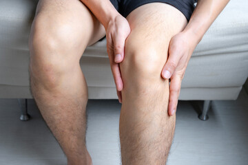 Man with knee pain, he puts his hand on his knee, pain point from osteoarthritis and...