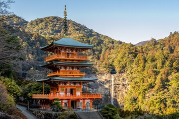 Imagine a serene temple nestled amidst the rugged slopes of a mountain, its ancient architecture blending harmoniously with the natural landscape.
 - obrazy, fototapety, plakaty