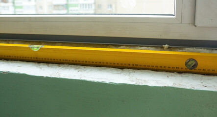 A close-up view showcasing the use of a yellow spirit level tool, strategically placed on a window...