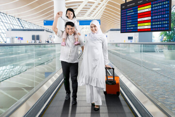 Muslim family walking with a suitcase on the airport moving walkways