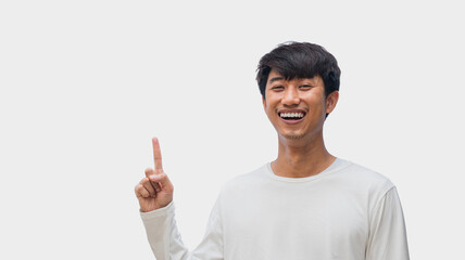 A young Asian man in his 20s wearing a white t-shirt happy smiling pointing thumbs up isolated on a...
