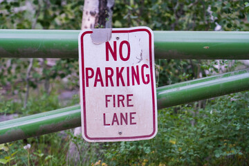 "No Parking -- Fire Lane" sign attached to gate on forest road.  