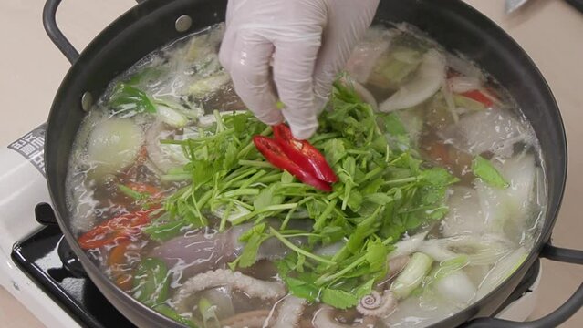 전골 냄비에 끓고 있는 낚지와 야채가 담긴 연포탕에 빨간 고추와 참깨를 올려 모양을 내는 