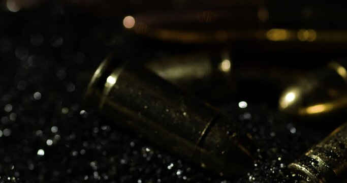 Close-up of 9mm and 300 BLK OUT bullets cascading down in slow motion, with a dark, moody backdrop