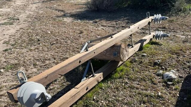 electrical distribution double wooden cross-arm with Hendrix vice top insulators attached laying on on the ground under construction
