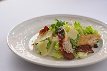 mixed leaf salad with bacon and chicken, parmesan dressing, white background, close-up view