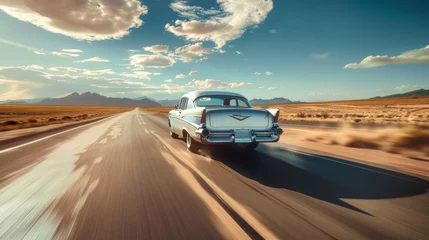 Papier Peint photo Lavable Voitures anciennes A white vintage sedan with iconic tailfins is captured on a desert highway, with a backdrop of mountains and a clear blue sky.