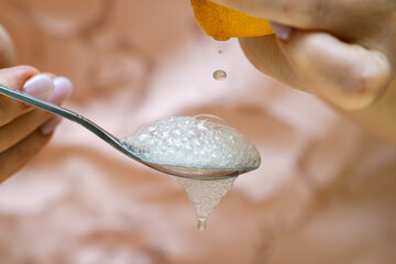 A squeezed drop of lemon juice flying into a spoon filled with baking soda. Abundant foam
