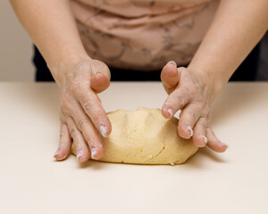 Women's hands knead the dough for making shortbread cookies