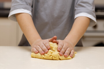 Obraz na płótnie Canvas boy's hands are pressing the cookie dough to the table