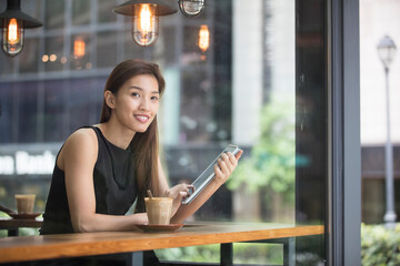 Asian Businesswoman reading her tablet computer in a cafe.