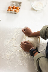 A young African American woman kneads dough on a floured surface with copy space