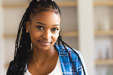 A young African American woman with braided hair smiles gently at the camera