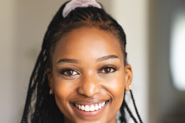 A young African American woman smiles brightly, her braided hair adorned with a headband
