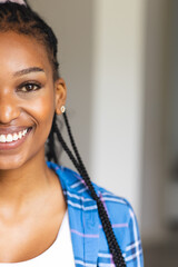 A young African American woman smiles warmly, her hair styled in braids