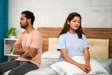 Angry Indian couple arguing each other at bedroom while sleeping - concept of family problems,...