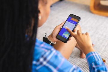 Young African American woman uses a smartphone, booking a vacation online