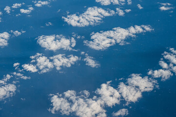 Aerial view of clouds and blue sky over ocean, cloudscape top view from airplane