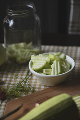 Preparation for homemade fermented food. Slicing zucchini (courgette) on a rustic table with curvy knife. Autumn harvest preservation