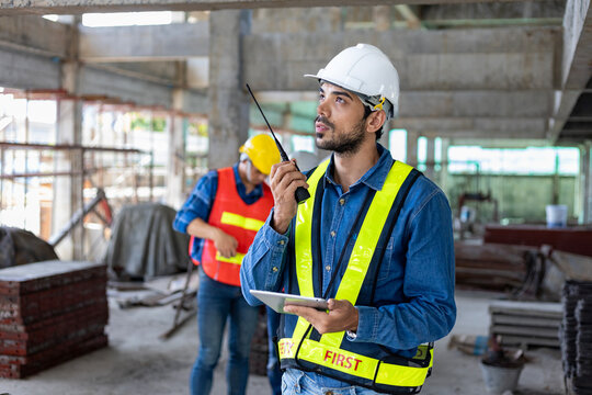 Caucasian engineer with radio walkie talkie in full safety gear is inspecting the crack and leak inside the building structure for investigation over specification and quality control