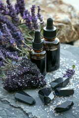 Two dark glass bottles with droppers surrounded by raw amethyst crystals and lavender sprigs on a slate background, hinting at natural wellness