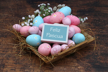 Firme con el texto “Felices Pascuas” en un nido con huevos de Pascua.