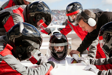 Race car driver gearing up for the big race with the pit crew team offering support. 